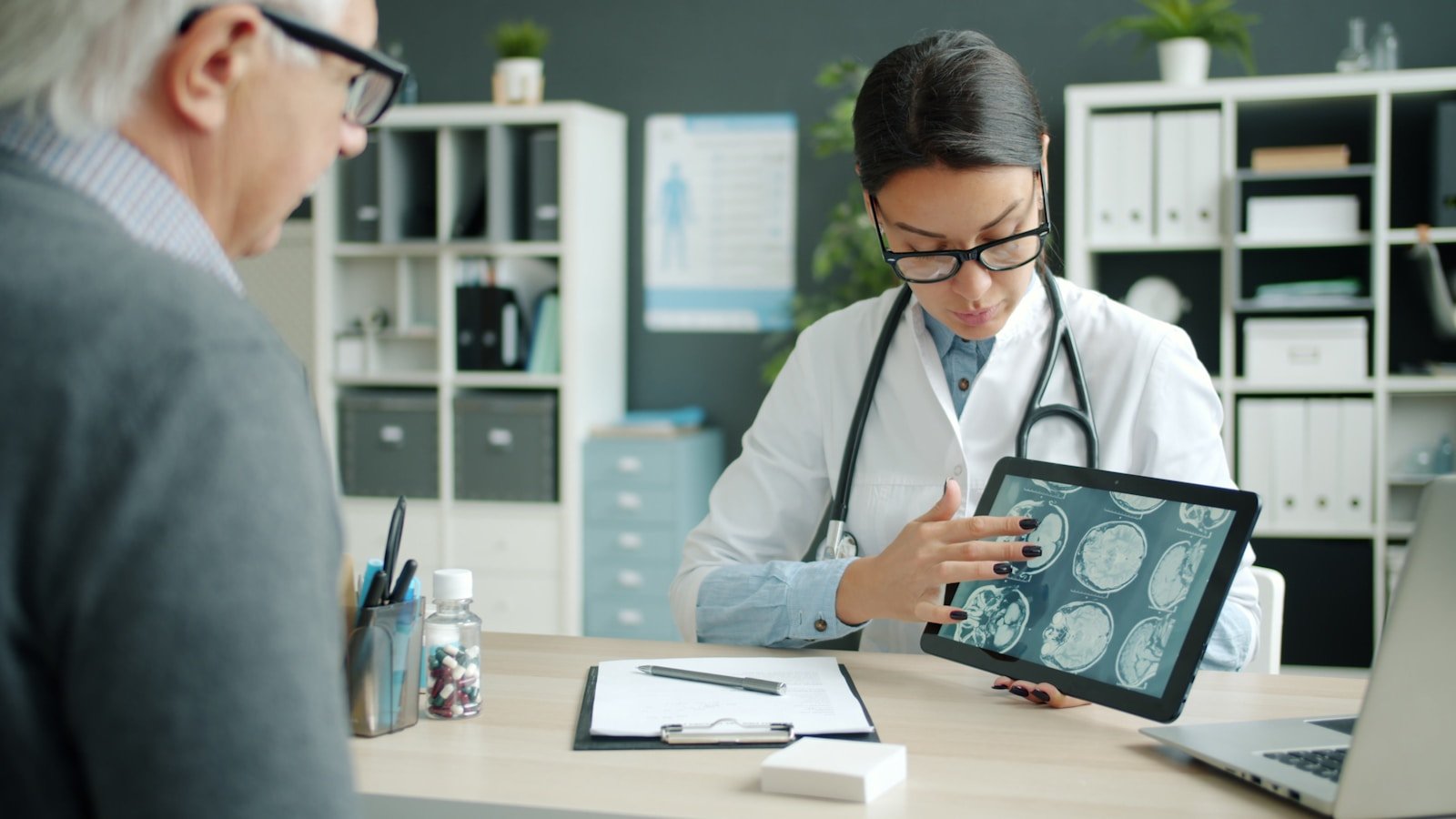 Doctor explaining medical scans on tablet to patient